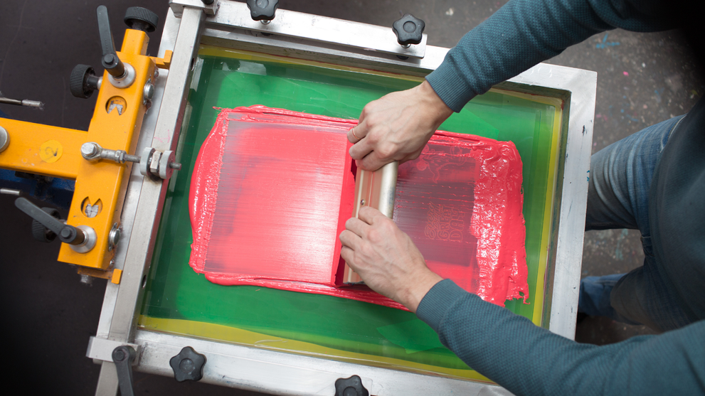Screen printing ink being spread with a squeegee on a mesh frame